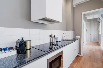 a kitchen with black counter tops and white cabinets at Apartments De Hallen in Amsterdam