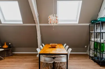 a dining room with a table and white chairs at Apartments De Hallen in Amsterdam