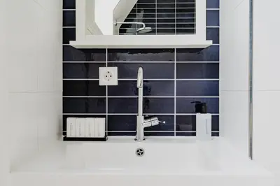 a kitchen with a sink and black tiles at Apartments De Hallen in Amsterdam