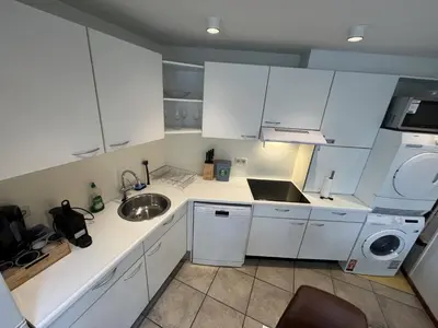 a small kitchen with white cabinets and a sink at Appartement Lijnden in Lijnden