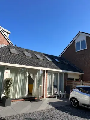a house with a car parked in the driveway at Appartement Lijnden in Lijnden