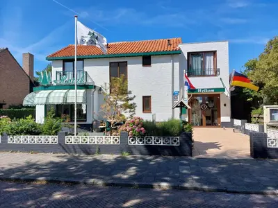 a white building with a flag in front of it at Hotel De Dennen in Egmond aan Zee