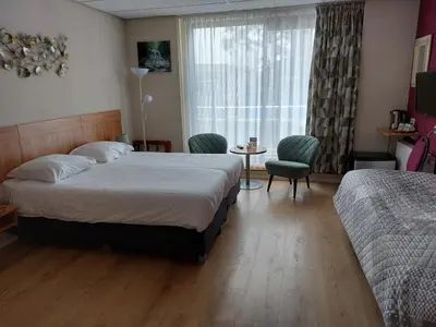 a hotel room with two beds and a window at Hotel De Dennen in Egmond aan Zee
