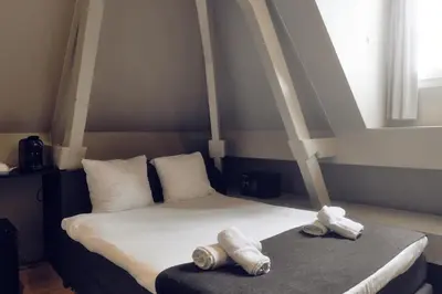 a bedroom with a bed with two towels on it at AmsterHome Hotel in Amsterdam