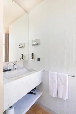 a white bathroom with a sink and a mirror at AmsterHome Hotel in Amsterdam