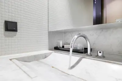 a white bathroom with a sink and a faucet at AmsterHome Hotel in Amsterdam