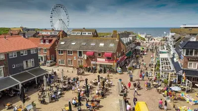 a crowd of people in a town with a ferris wheel at Bundi Beach in Egmond aan Zee