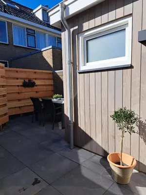 a patio with a window and a table with chairs at Bundi Beach in Egmond aan Zee