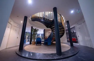 a spiral staircase in a building with blue chairs at MA Airport Hotel in Hoofddorp