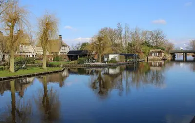 a view of a river with houses and a bridge at Braassermerhuis in Rijnsaterwoude