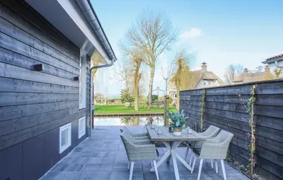 a patio with a table and chairs next to a wall at Braassermerhuis in Rijnsaterwoude