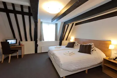 a bedroom with a bed and a desk with a computer at Ambassador City Centre Hotel in Haarlem