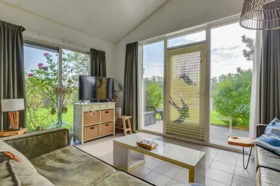 a living room with a tv and large windows at Rekerlanden 274 in Warmenhuizen