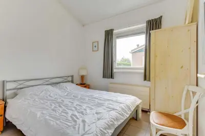 a bedroom with a bed and a window and a chair at Rekerlanden 274 in Warmenhuizen
