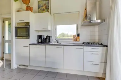 a white kitchen with white cabinets and a window at Rekerlanden 274 in Warmenhuizen