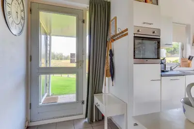 a kitchen with a window and a clock on the wall at Rekerlanden 274 in Warmenhuizen