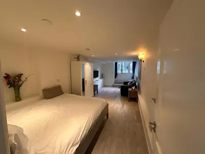 a bedroom with a white bed and a living room at Luxury House With 2 Private Independent Studios 120 m2 Near LEIDSEPLEIN CITY CENTRE AMSTERDAM - Paid Parking Possibilities Nearby in Amsterdam
