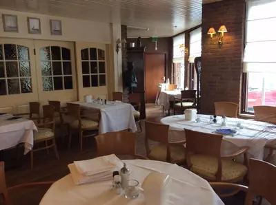 a dining room with tables and chairs with white tablecloths at Hotel de Admiraal in Noordwijk aan Zee