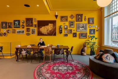 a woman sitting at a table in a room with yellow walls at Stayokay Hostel Amsterdam Stadsdoelen in Amsterdam