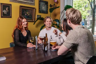 a group of people sitting around a table with drinks at Stayokay Hostel Amsterdam Stadsdoelen in Amsterdam