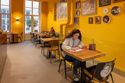 a woman sitting at a table in a restaurant at Stayokay Hostel Amsterdam Stadsdoelen in Amsterdam