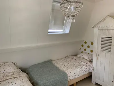 a bedroom with two twin beds and a chandelier at ´t Kappershuis in Groet