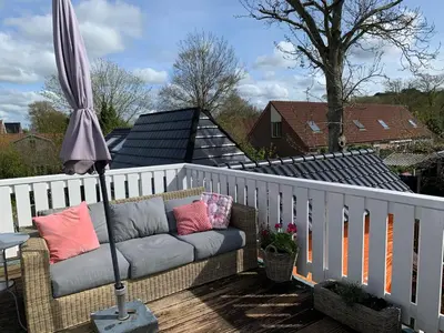 a couch on a balcony with an umbrella at ´t Kappershuis in Groet