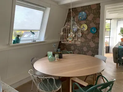 a dining room with a wooden table and chairs at ´t Kappershuis in Groet