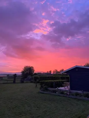 a sunset in a field with a building and a sky at Amsterdam The Stables in Oostzaan