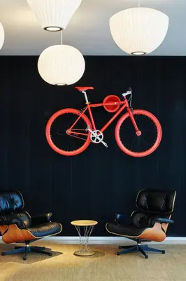 a red bike hanging from a wall with chairs and chairs at citizenM Schiphol Airport in Schiphol