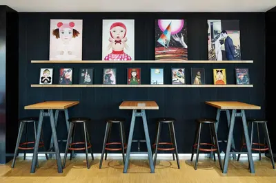 a row of bar stools against a wall with pictures at citizenM Schiphol Airport in Schiphol