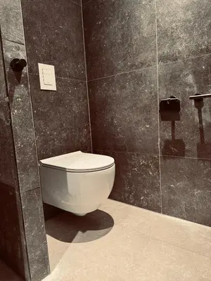 a bathroom with a toilet in a black tiled wall at Boutique Hotel Hans - Amsterdam Schiphol Airport in Badhoevedorp