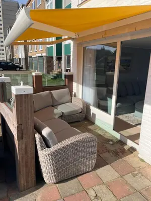 a patio with a couch and chairs under an awning at Strandzicht Zandvoort Boulevard Apartments in Zandvoort