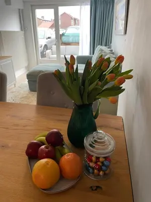 a table with a plate of fruit and a vase with flowers at Strandzicht Zandvoort Boulevard Apartments in Zandvoort