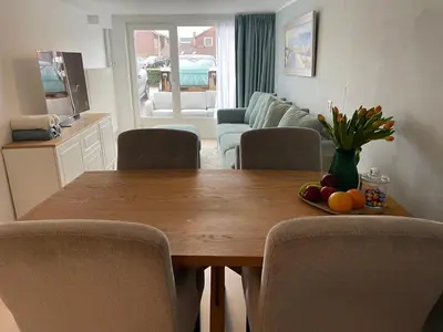 a dining room table with chairs and a table with fruit on it at Strandzicht Zandvoort Boulevard Apartments in Zandvoort