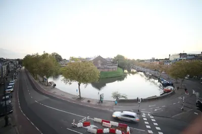 a city street with a river with cars on the road at B&B de singel in Utrecht