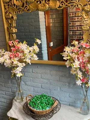 a table with two vases with flowers and a mirror at Hotel Oorsprongpark City Centre Utrecht in Utrecht