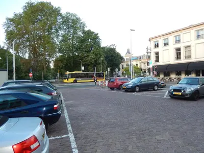 a parking lot with parked cars and a yellow bus at Hotel Oorsprongpark City Centre Utrecht in Utrecht