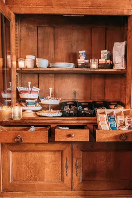 a wooden cabinet with plates and dishes on it at Hotel Café Restaurant Abina in Amstelveen