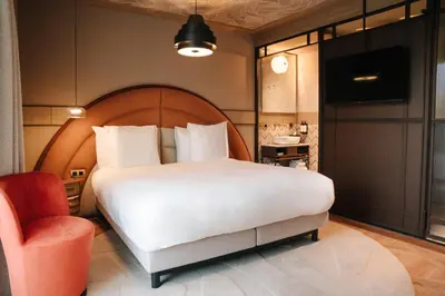 a bedroom with a large white bed and a chair at The Diamond Amsterdam in Amsterdam