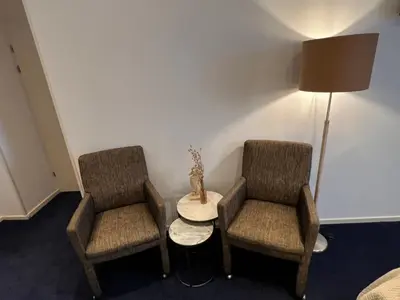 two chairs and a table in a room with a lamp at SEA YOU Hotel Noordwijk in Noordwijk aan Zee