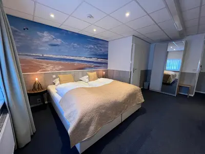a bedroom with a large bed with a painting on the wall at SEA YOU Hotel Noordwijk in Noordwijk aan Zee
