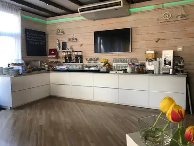 a kitchen with white cabinets and a flat screen tv at SEA YOU Hotel Noordwijk in Noordwijk aan Zee
