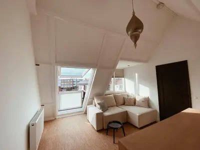 a living room with a white couch and a window at LONG BEACH ROOMS 3 in Zandvoort
