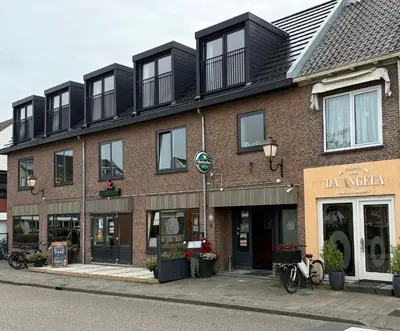 a large brick building with black windows on a street at Eetcafé Punt in Roelofarendsveen