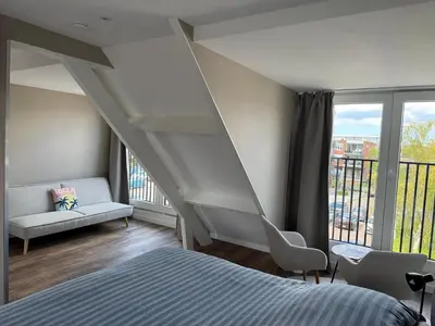 a bedroom with a staircase and a bed and a window at Eetcafé Punt in Roelofarendsveen