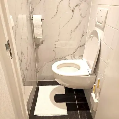 a bathroom with a white toilet and a marble wall at Charming Apartment in Lisse - 30 sqm with Terrace in Lisse