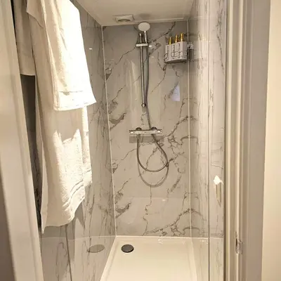 a bathroom with a shower with a marble tile wall at Charming Apartment in Lisse - 30 sqm with Terrace in Lisse