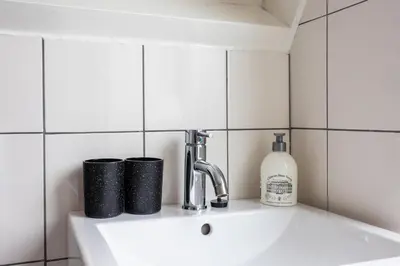 a sink in a bathroom with a bottle of soap at Tulip Marina - garden sauna in Nieuwe-Niedorp