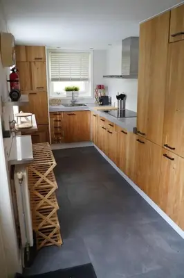 a large kitchen with wooden cabinets and a window at Het Warme nest in Noordwijkerhout